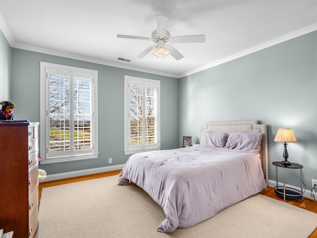 bedroom featuring wood finished floors, baseboards, ornamental molding, and visible vents