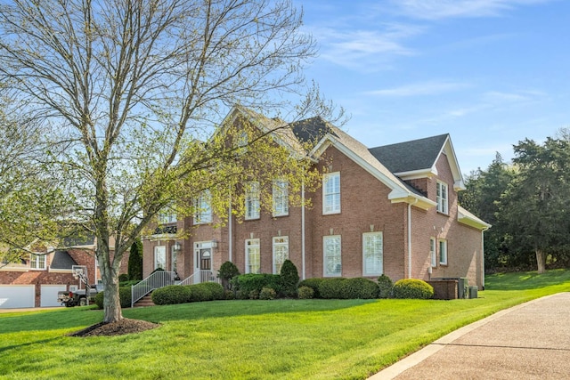 view of front of home with brick siding, a front yard, and central AC unit