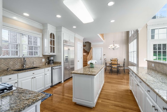 kitchen with a center island, crown molding, decorative backsplash, stainless steel appliances, and a sink