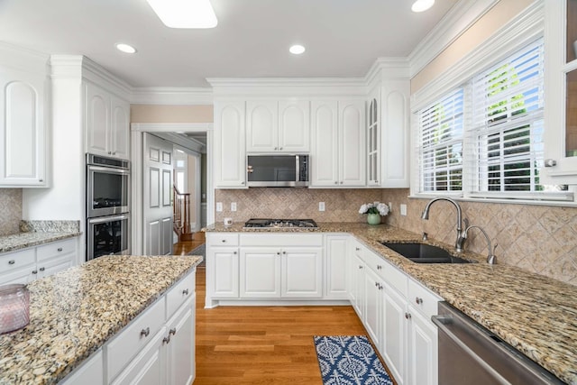 kitchen featuring white cabinets, light wood-style flooring, a sink, and appliances with stainless steel finishes