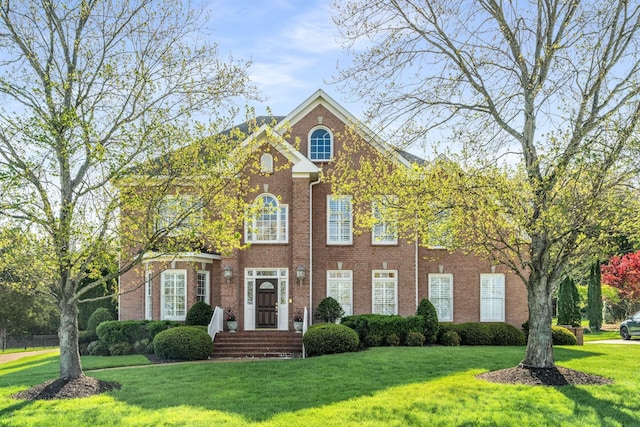 view of front facade with a front yard and brick siding
