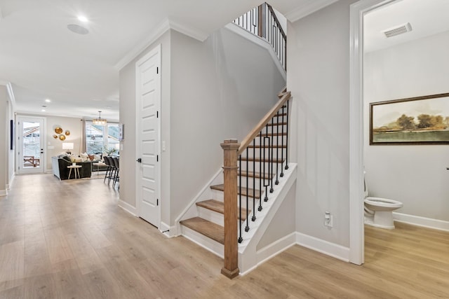 staircase with wood-type flooring and crown molding