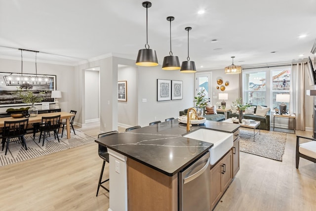 kitchen with pendant lighting, stainless steel dishwasher, light wood-type flooring, and a kitchen island with sink