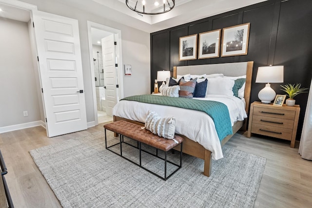 bedroom with a chandelier, light hardwood / wood-style floors, and ensuite bath