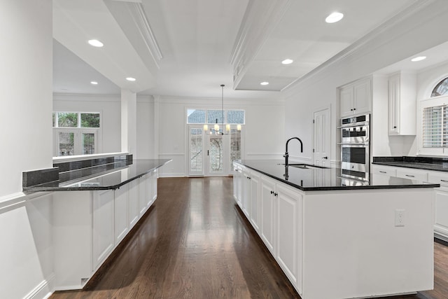 kitchen with a wealth of natural light, a center island with sink, hanging light fixtures, and sink