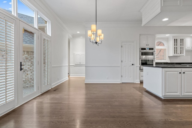 kitchen featuring white cabinetry, stainless steel double oven, hanging light fixtures, a notable chandelier, and ornamental molding