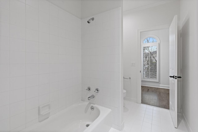 bathroom featuring tile patterned flooring, toilet, and tiled shower / bath