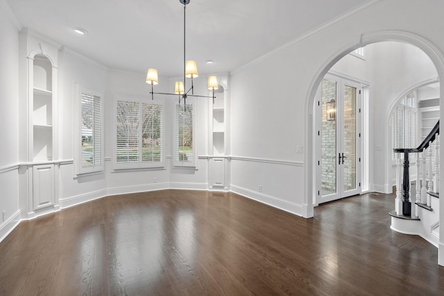 unfurnished dining area featuring an inviting chandelier, french doors, crown molding, dark hardwood / wood-style floors, and built in features