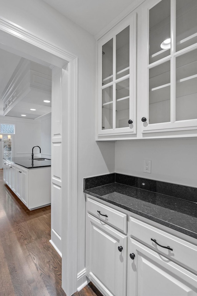 bar featuring dark hardwood / wood-style floors, white cabinetry, and dark stone counters