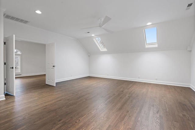 additional living space featuring dark hardwood / wood-style floors, lofted ceiling with skylight, and ceiling fan