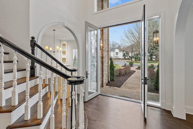 foyer entrance with dark wood-type flooring, a wealth of natural light, and a chandelier