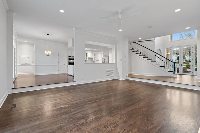 unfurnished living room with french doors, ceiling fan with notable chandelier, dark wood-type flooring, and ornamental molding