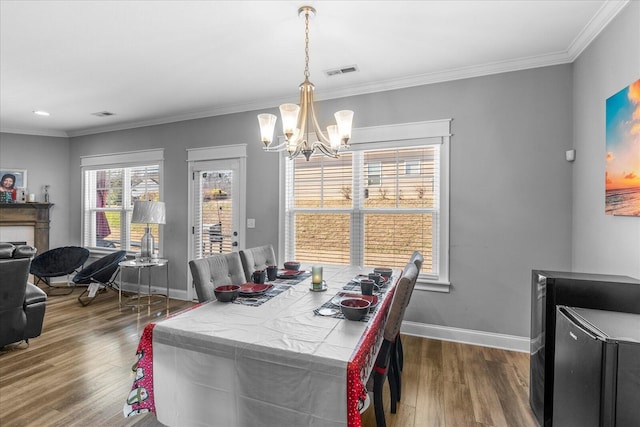 dining area with crown molding, wood-type flooring, and a notable chandelier