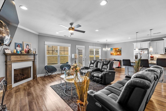 living room with a textured ceiling, ceiling fan with notable chandelier, crown molding, and hardwood / wood-style flooring