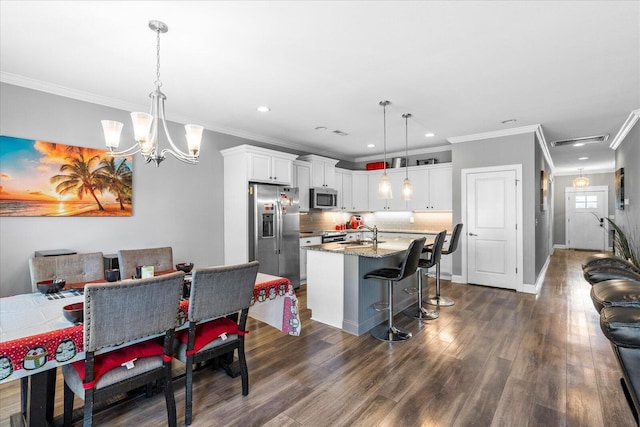 dining space with sink, dark wood-type flooring, crown molding, and a notable chandelier