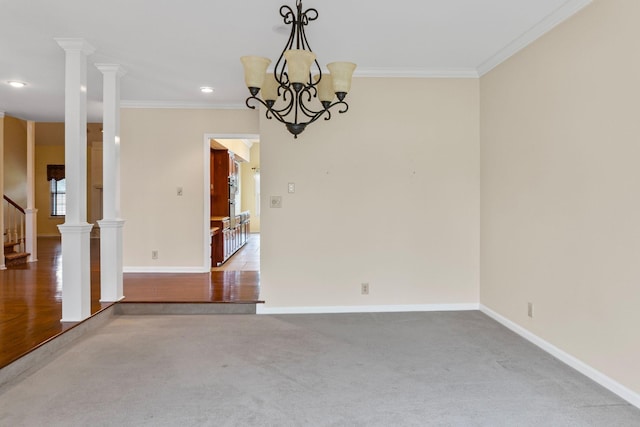 carpeted spare room with ornamental molding, a chandelier, and ornate columns