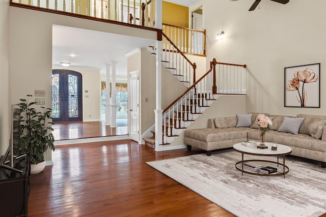 living room with decorative columns, crown molding, wood-type flooring, and french doors