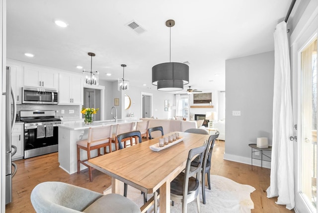 dining area with ceiling fan, sink, a wealth of natural light, and light hardwood / wood-style flooring