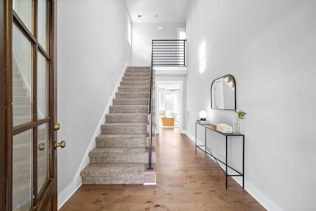 stairway featuring hardwood / wood-style floors and a towering ceiling