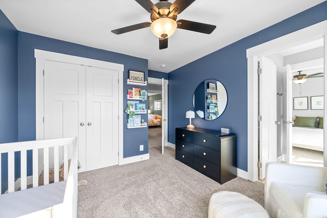 carpeted bedroom featuring ceiling fan, a crib, and a closet