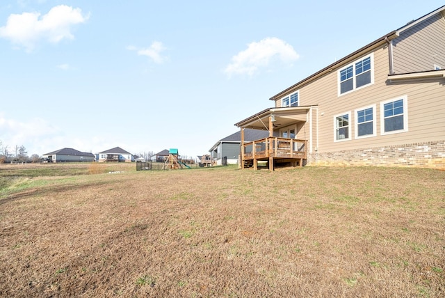 back of house with a yard, a playground, and a wooden deck