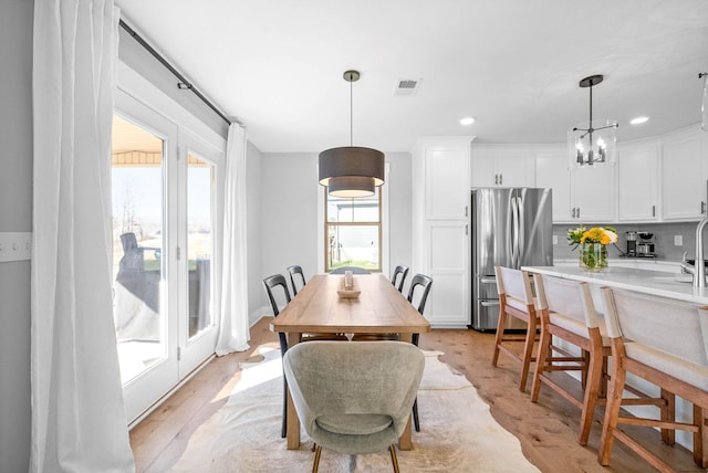 dining room featuring light wood-type flooring and a notable chandelier