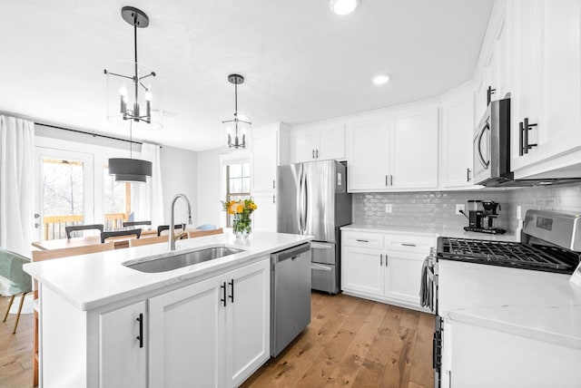 kitchen featuring white cabinetry, stainless steel appliances, and an island with sink