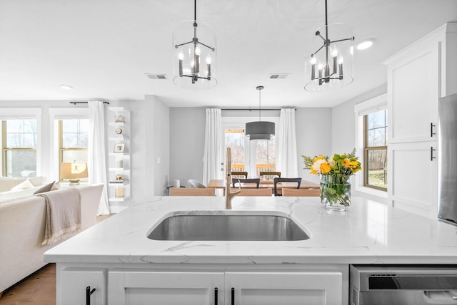 kitchen with white cabinets, decorative light fixtures, light stone countertops, and a wealth of natural light