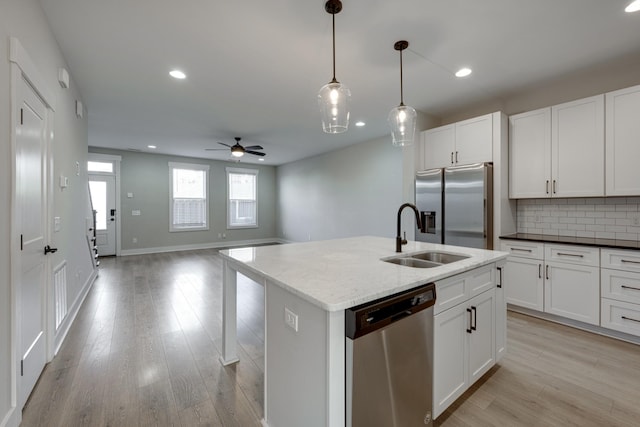 kitchen with appliances with stainless steel finishes, tasteful backsplash, ceiling fan, sink, and an island with sink