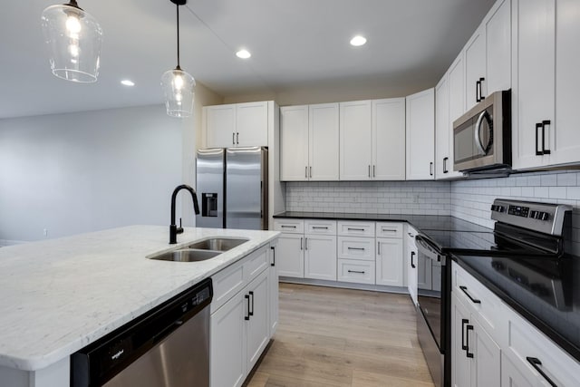 kitchen with appliances with stainless steel finishes, white cabinetry, and a kitchen island with sink