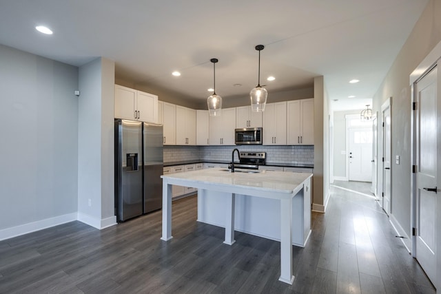 kitchen featuring a breakfast bar, white cabinets, sink, appliances with stainless steel finishes, and decorative light fixtures