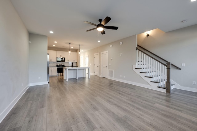 unfurnished living room featuring ceiling fan and light wood-type flooring