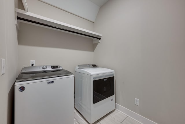 clothes washing area with washing machine and clothes dryer and light tile patterned floors