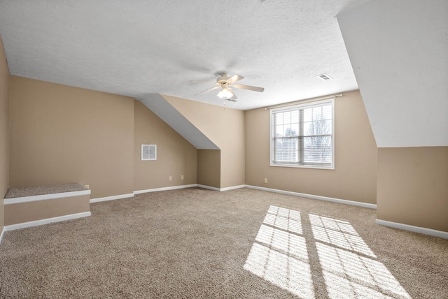 bonus room featuring a textured ceiling, light colored carpet, vaulted ceiling, and ceiling fan