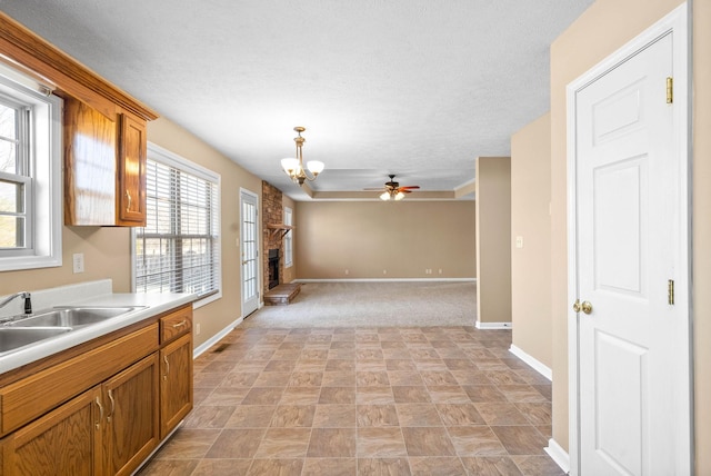 kitchen featuring pendant lighting, ceiling fan with notable chandelier, sink, and a fireplace