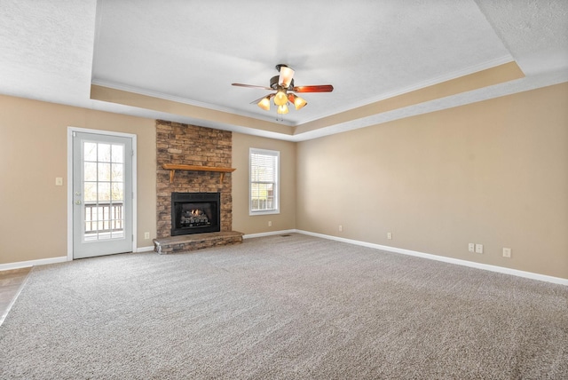 unfurnished living room featuring a fireplace, carpet, a tray ceiling, and ceiling fan