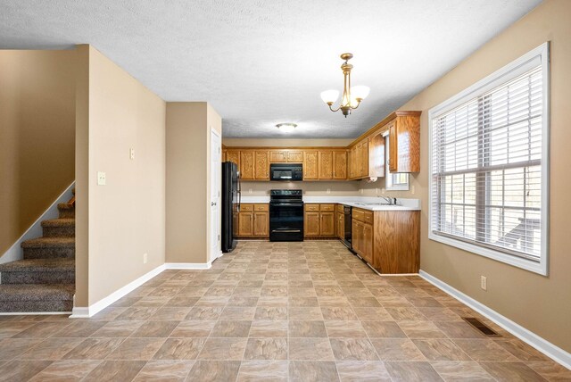 kitchen featuring black appliances, plenty of natural light, sink, and hanging light fixtures