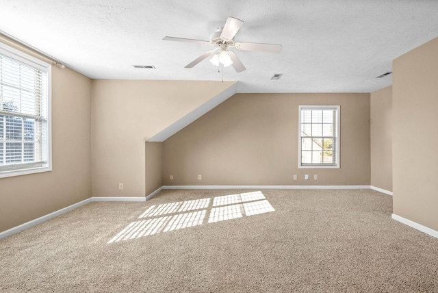 additional living space with carpet flooring, a textured ceiling, ceiling fan, and lofted ceiling