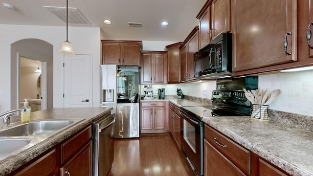 kitchen with backsplash, black appliances, sink, decorative light fixtures, and dark hardwood / wood-style flooring