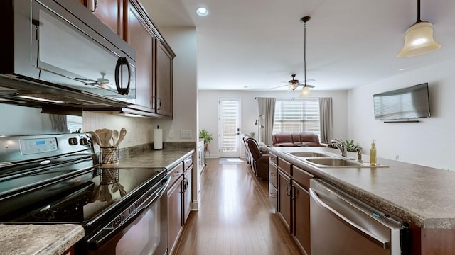 kitchen with dishwasher, sink, hanging light fixtures, black / electric stove, and light wood-type flooring