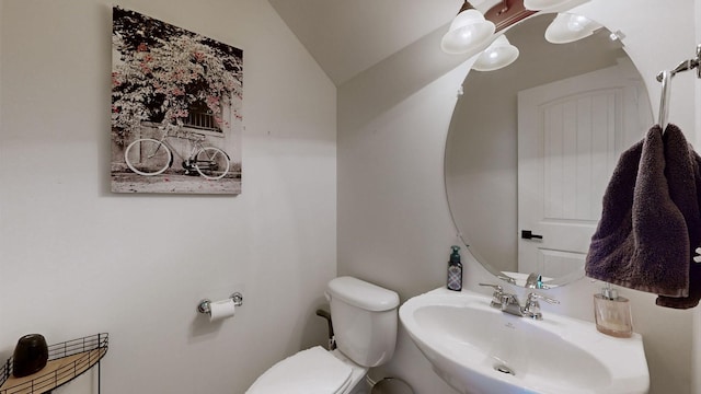 bathroom with toilet, lofted ceiling, and sink