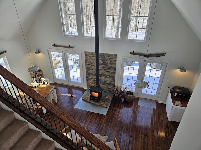 living room featuring a wood stove, a wealth of natural light, french doors, a high ceiling, and dark hardwood / wood-style floors