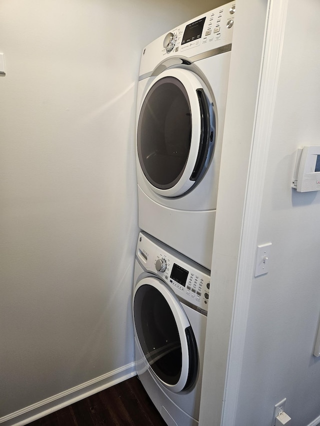 clothes washing area with stacked washer / dryer and dark wood-type flooring