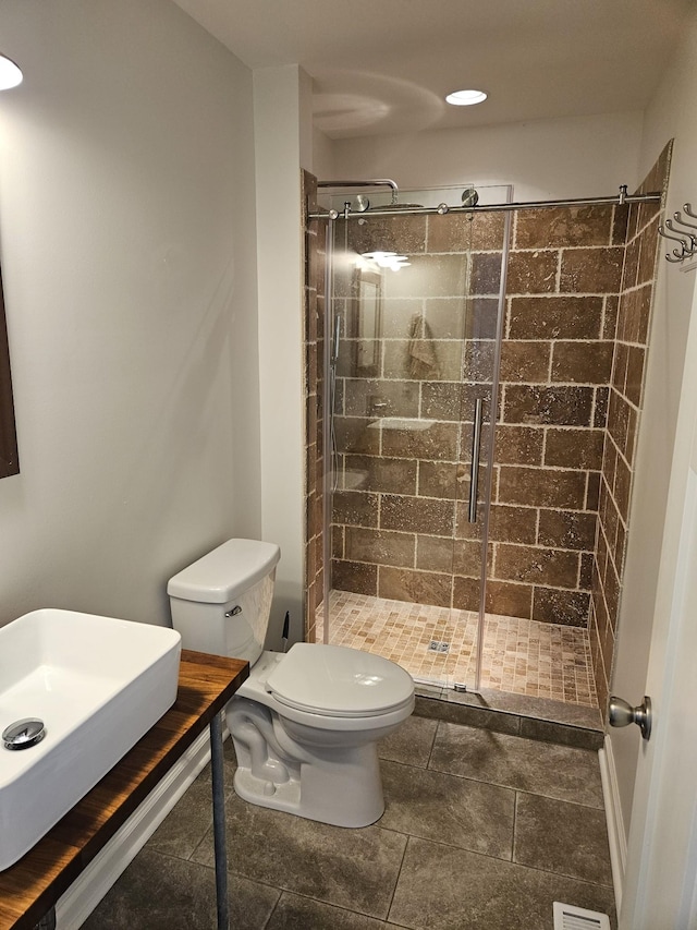 bathroom with sink, a shower with door, and toilet