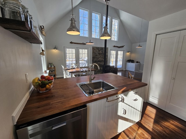 kitchen with pendant lighting, french doors, wooden counters, sink, and stainless steel dishwasher