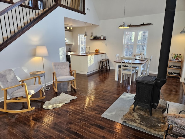 living room with dark hardwood / wood-style floors, a healthy amount of sunlight, a wood stove, and high vaulted ceiling