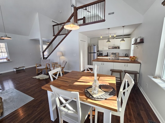 dining space with dark hardwood / wood-style flooring, high vaulted ceiling, and sink