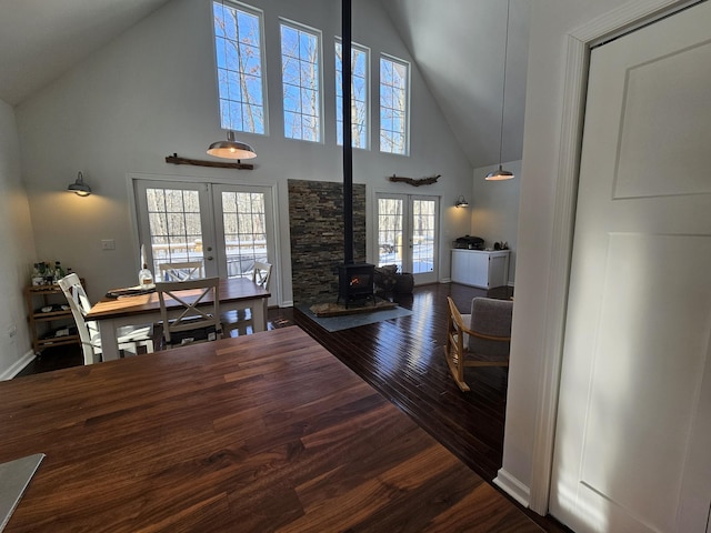 living room featuring a wood stove, french doors, a towering ceiling, and dark hardwood / wood-style floors