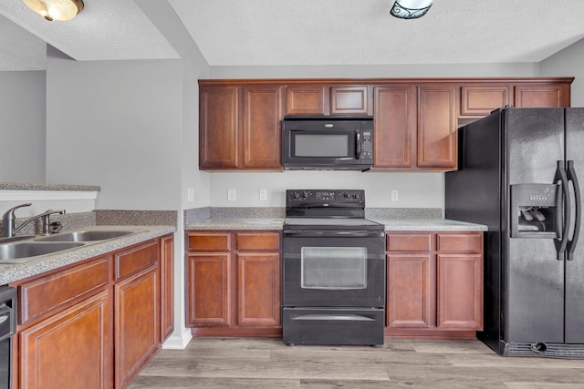 kitchen with light wood-type flooring, a textured ceiling, sink, and black appliances