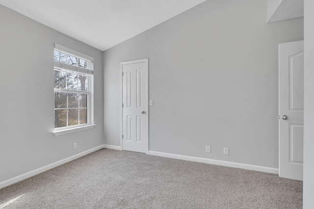 unfurnished room with carpet flooring and vaulted ceiling